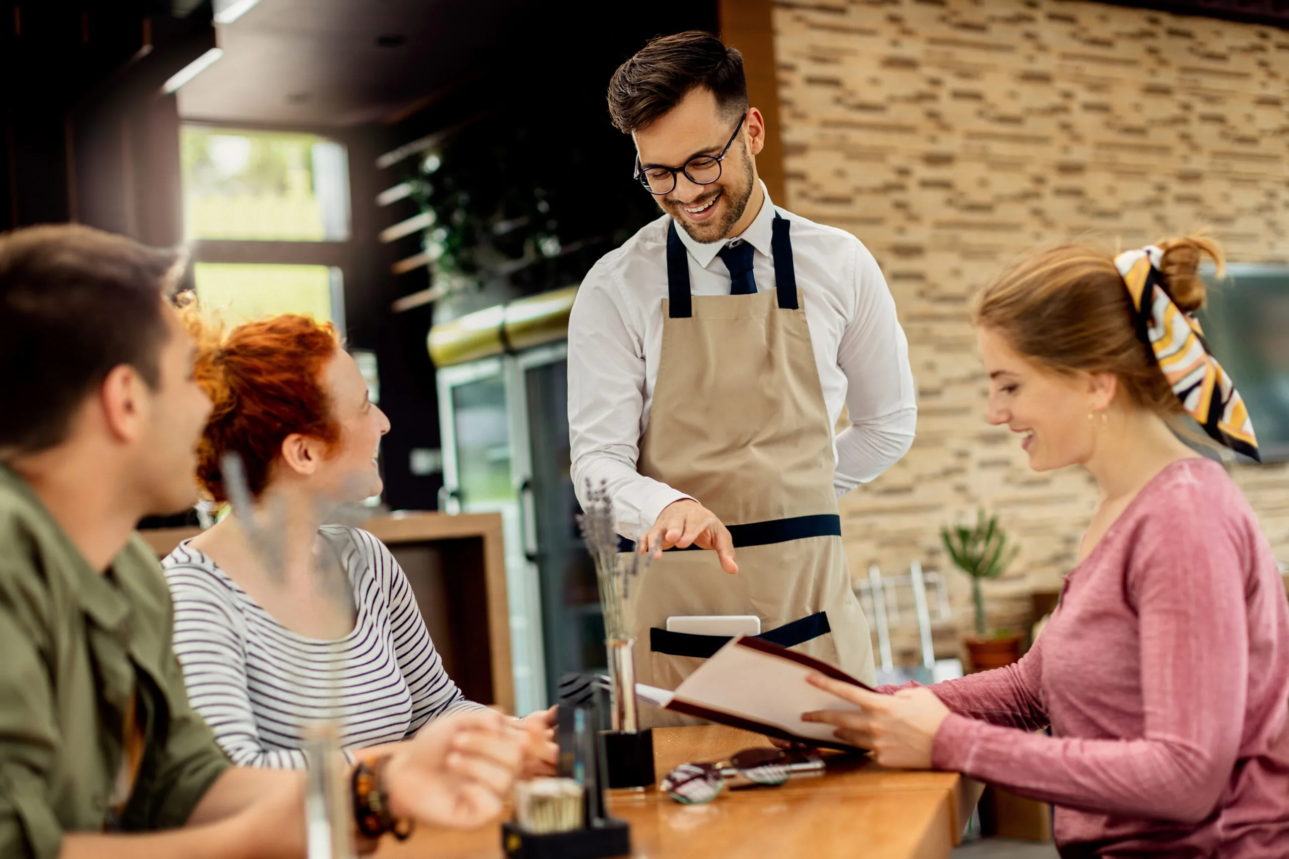 mozo2 Happy waiter having fun while talking to his guests and taking order from them in a cafe,